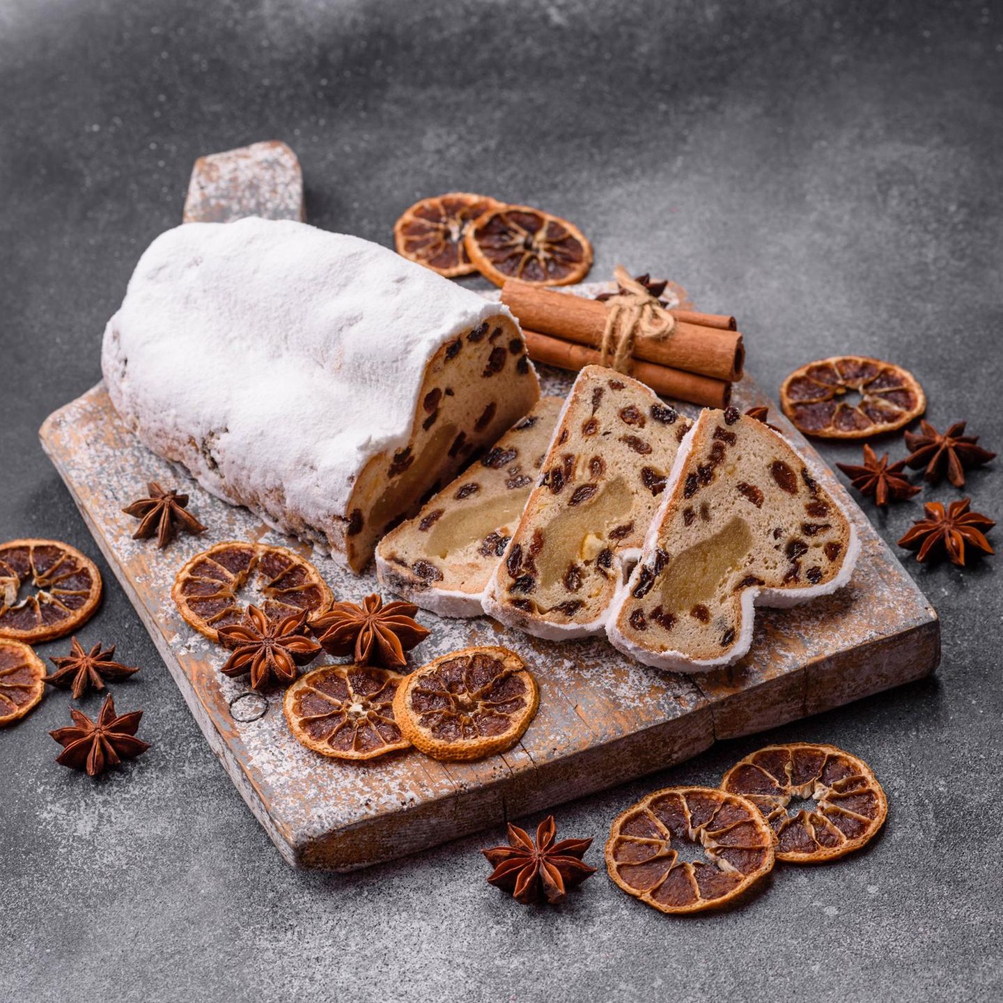 Angeschnittener Christstollen mit Puderzucker auf einem Holzbrett