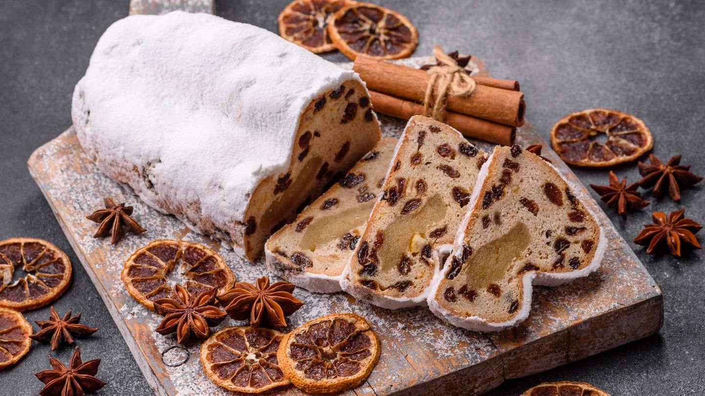 Angeschnittener Christstollen mit Puderzucker auf einem Holzbrett