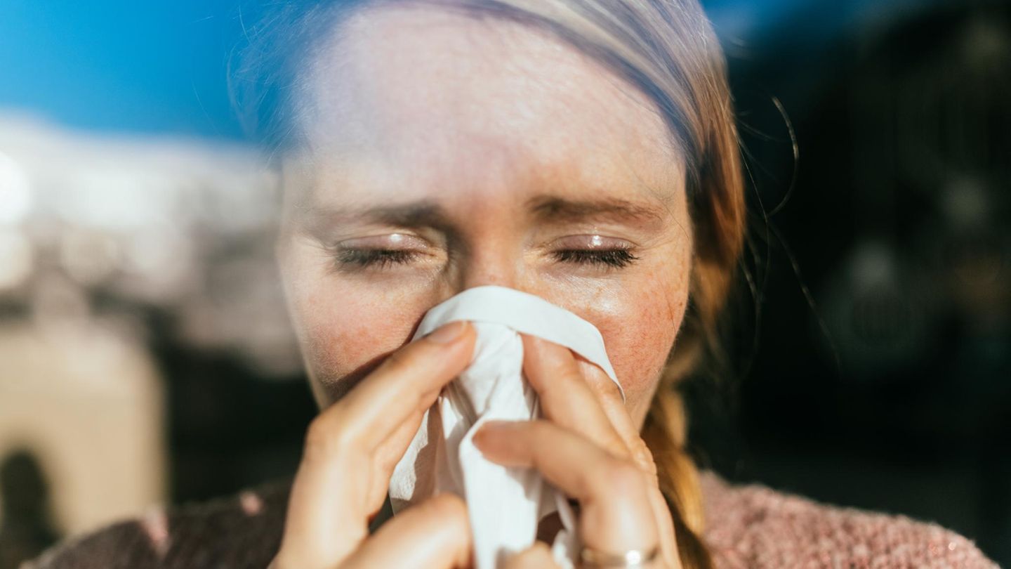 Grippevirus: eine Frau putzt sich die Nase