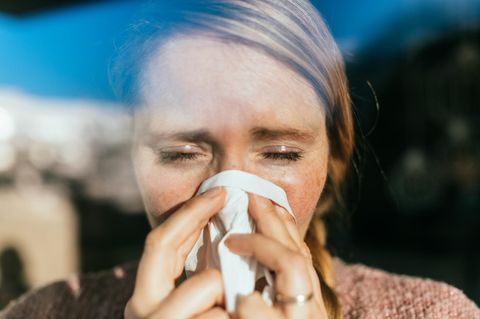 Grippevirus: eine Frau putzt sich die Nase