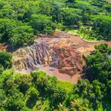 Eine Luftaufnahme der Siebenfarbigen Erde auf Mauritius, bei dem sich die bunte Landschaft vom umgebenden Wald abhebt