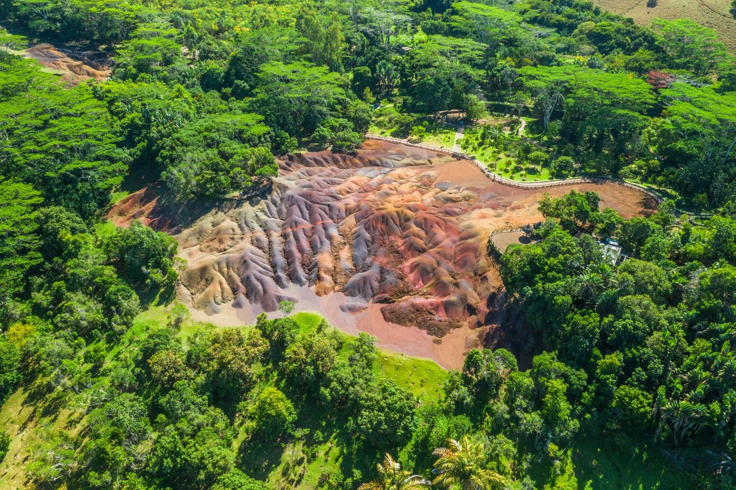 Eine Luftaufnahme der Siebenfarbigen Erde auf Mauritius, bei dem sich die bunte Landschaft vom umgebenden Wald abhebt
