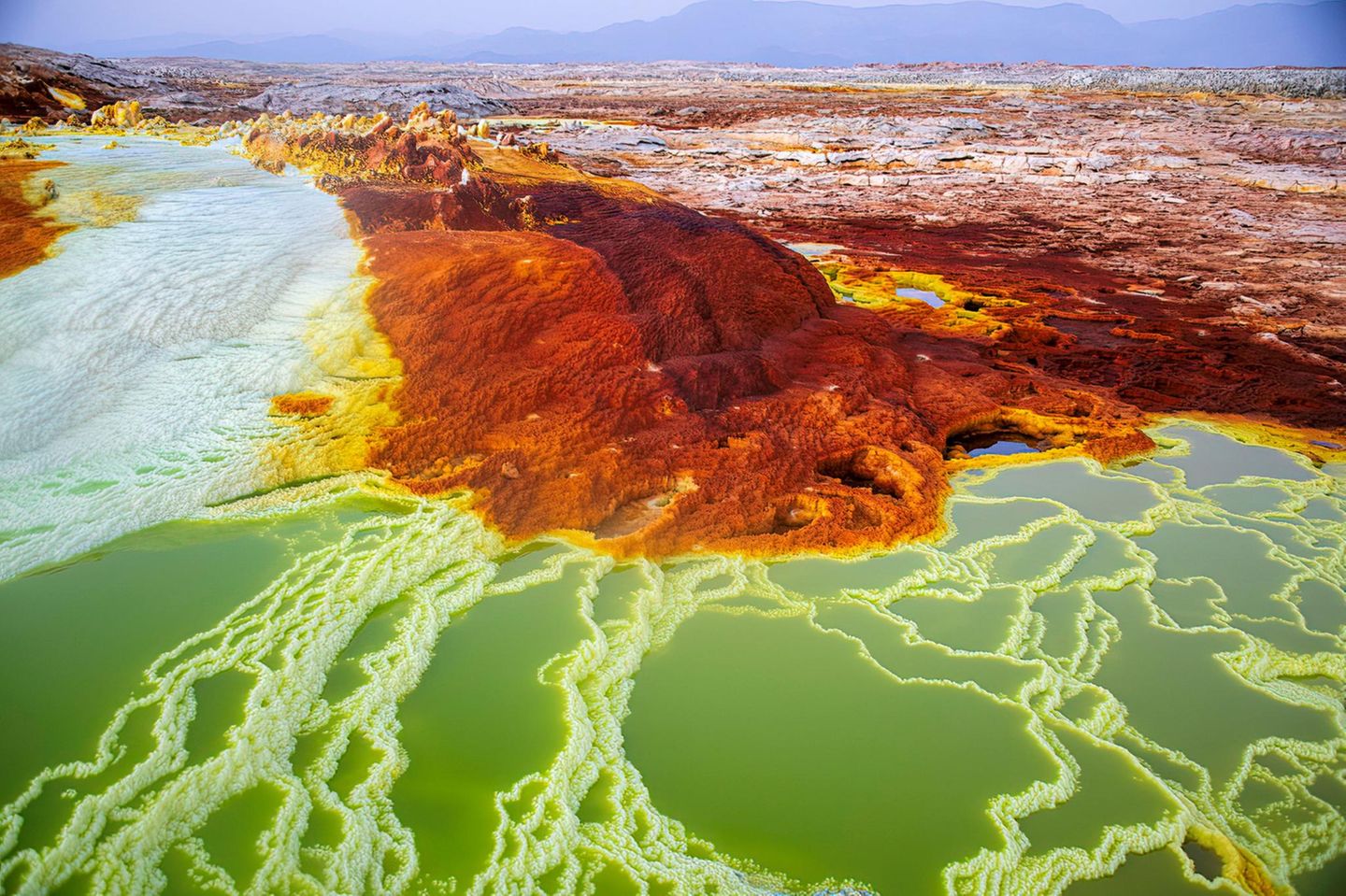 Die rot-braune Dallol Vulkanlandschaft, welche von weißen bis blauen Naturbecken und Salztürmen durchsäht ist