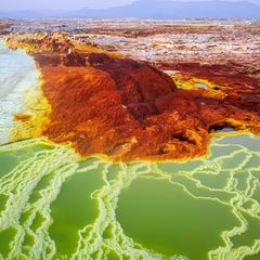 Die rot-braune Dallol Vulkanlandschaft, welche von weißen bis blauen Naturbecken und Salztürmen durchsäht ist