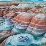 Eine Hügellandschaft, welche durch Gesteinsschichten in unterschiedlichen Farben sehr bunt wird