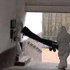 Beamte der Spurensicherung bringen eine Trage in ein Wohnhaus. Foto: Thorsten Kremers/dpa