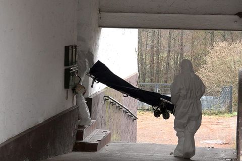 Beamte der Spurensicherung bringen eine Trage in ein Wohnhaus. Foto: Thorsten Kremers/dpa