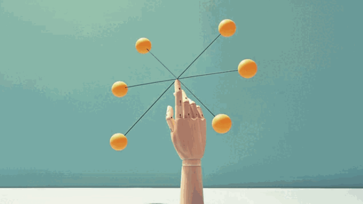 Eine Hand balanciert ein Objekt mit Kugeln auf der Fingerspitze