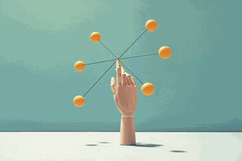 Eine Hand balanciert ein Objekt mit Kugeln auf der Fingerspitze