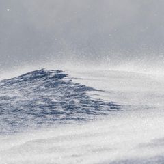 Ein Schneesturm peitscht über eine Bergkuppe