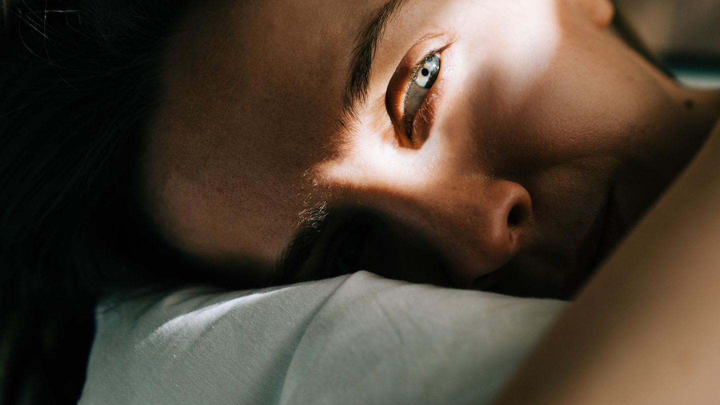 Frau liegt auf dem Bett und schaut aus dem Bild heraus