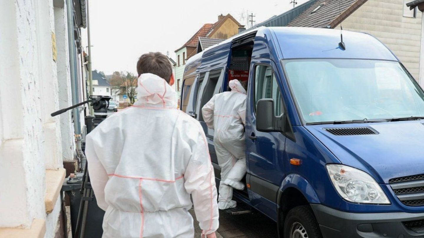 Zwei Mitarbeiter der Spurensicherung besteigen im Saarland in weißen Overalls einen blauen Transporter