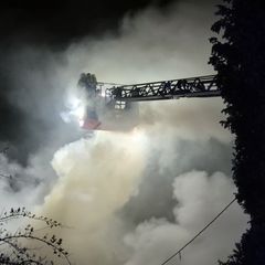 Einsatzkräfte der Feuerwehr löschen von einer Drehleiter den Brand in einem Wohnhaus. Foto: Sascha Thelen/dpa