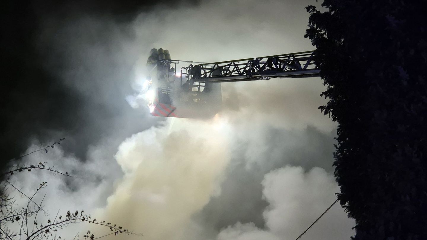 Einsatzkräfte der Feuerwehr löschen von einer Drehleiter den Brand in einem Wohnhaus. Foto: Sascha Thelen/dpa