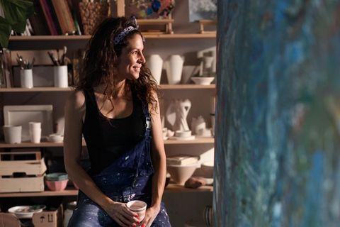 Eine Künstlerin sitzt auf einem Barhocker und macht Pause (Symbolbild Kunstlehrerin im Referendariat)