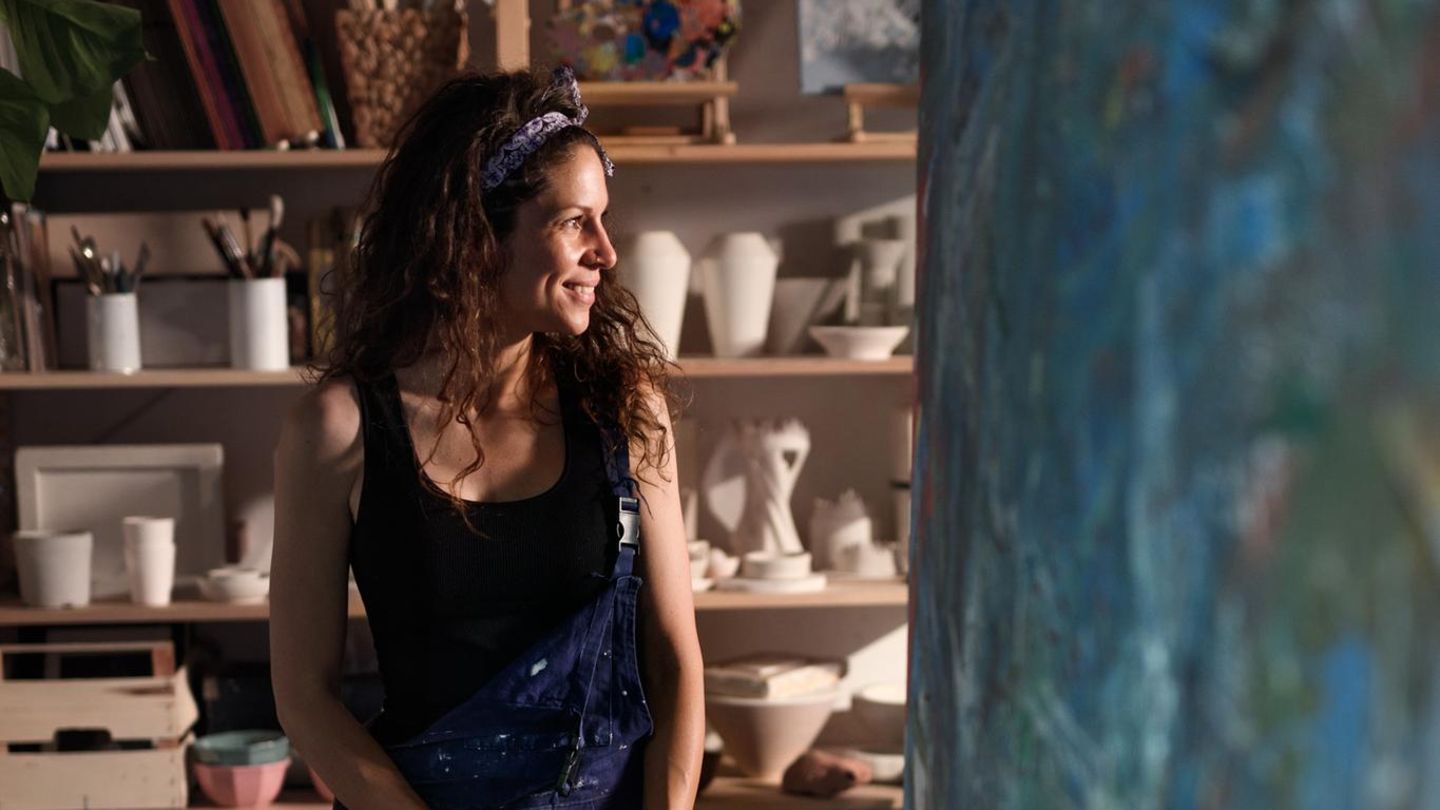 Eine Künstlerin sitzt auf einem Barhocker und macht Pause (Symbolbild Kunstlehrerin im Referendariat)