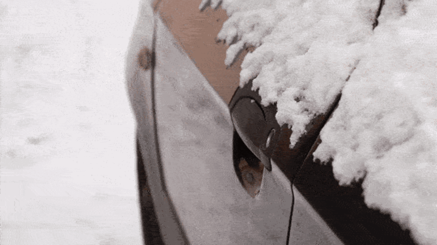 Ein Mann versucht im Winter sein Auto mit dem Schlüssel zu öffnen