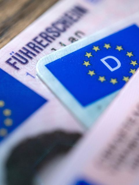 Mehrere Führerscheine liegen übereinander auf einem Holztisch