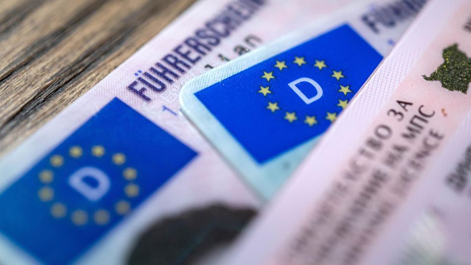 Mehrere Führerscheine liegen übereinander auf einem Holztisch
