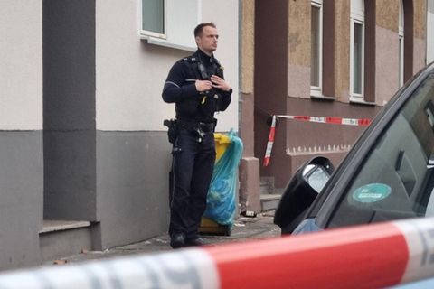 Ein Polizist steht vor dem Mietshaus in Düsseldorf, in dem die Leichen der Frau und des Kindes entdeckt wurden