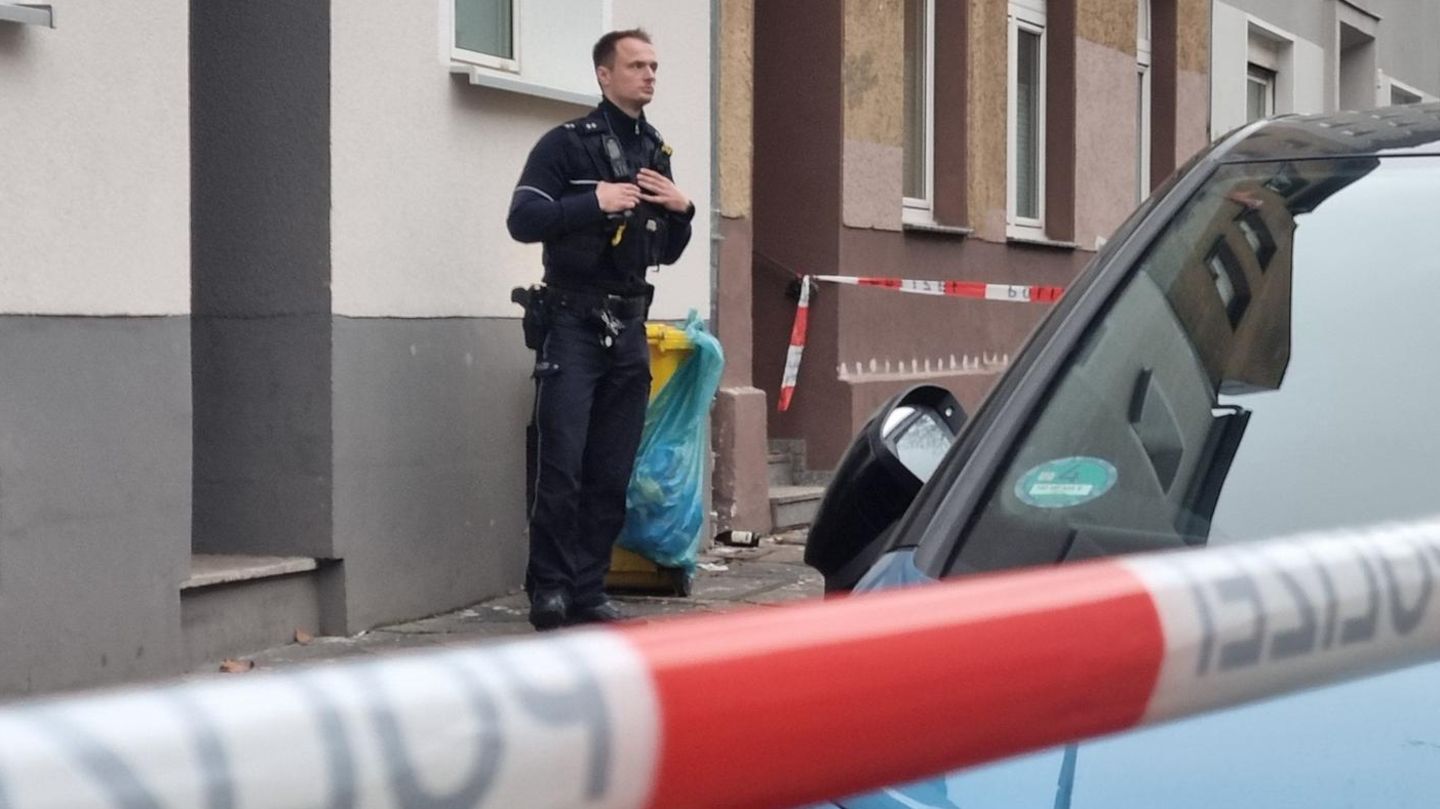 Ein Polizist steht vor dem Mietshaus in Düsseldorf, in dem die Leichen der Frau und des Kindes entdeckt wurden