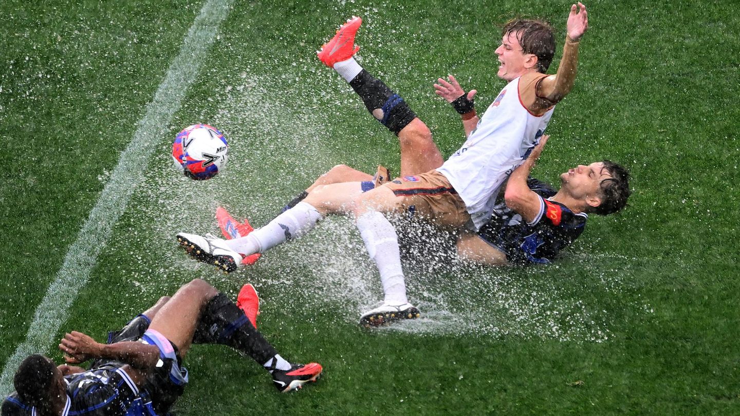 Fußballer im Kampf um den Ball, während das Wasser spritzt