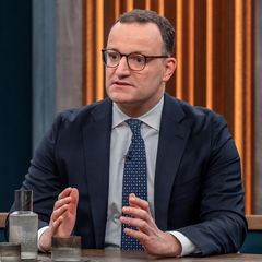 Jens Spahn sitzt an einem Tisch mit Caren Miosga und gestikuliert mit beiden Händen beim Reden
