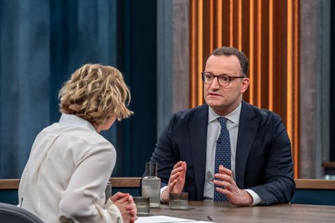 Jens Spahn sitzt an einem Tisch mit Caren Miosga und gestikuliert mit beiden Händen beim Reden