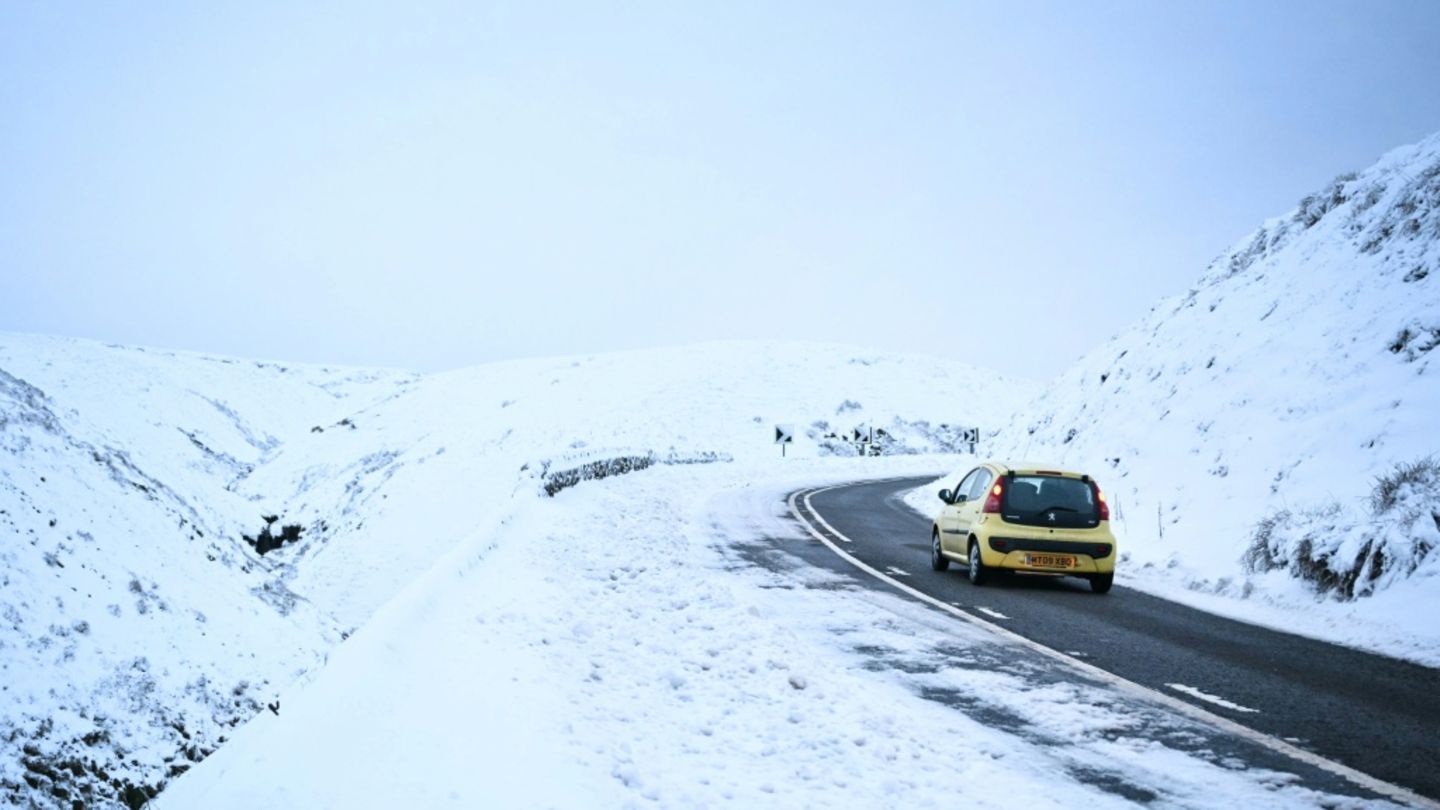 Auto fährt an verschneiter Straße entlang