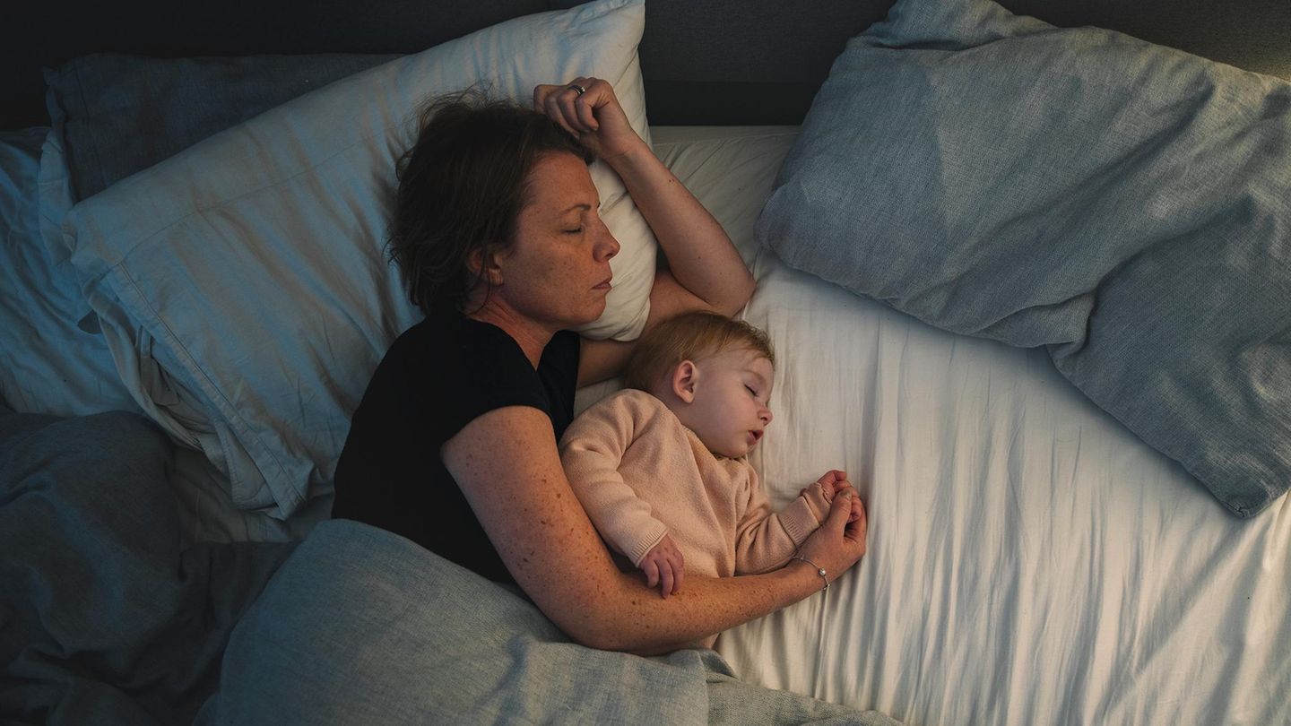 Eine junge Mutter liegt alleine mit ihrem Kind im Bett. Partnerschaft