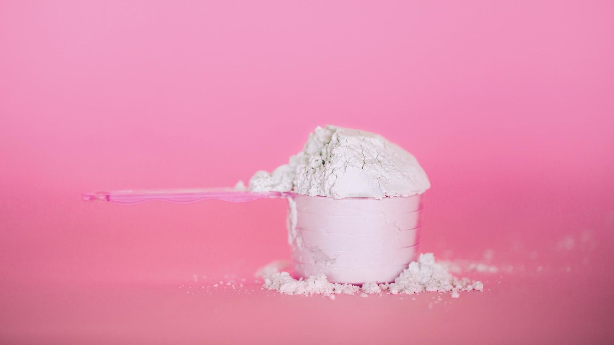 Proteinpulver auf pinkem Untergrund