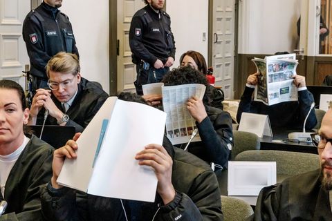 Die Angeklagten im Prozess verbergen ihre Gesichter vor den Fotografen. Foto: Markus Scholz/dpa