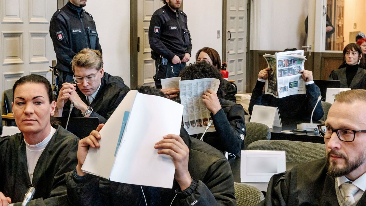 Die Angeklagten im Prozess verbergen ihre Gesichter vor den Fotografen. Foto: Markus Scholz/dpa