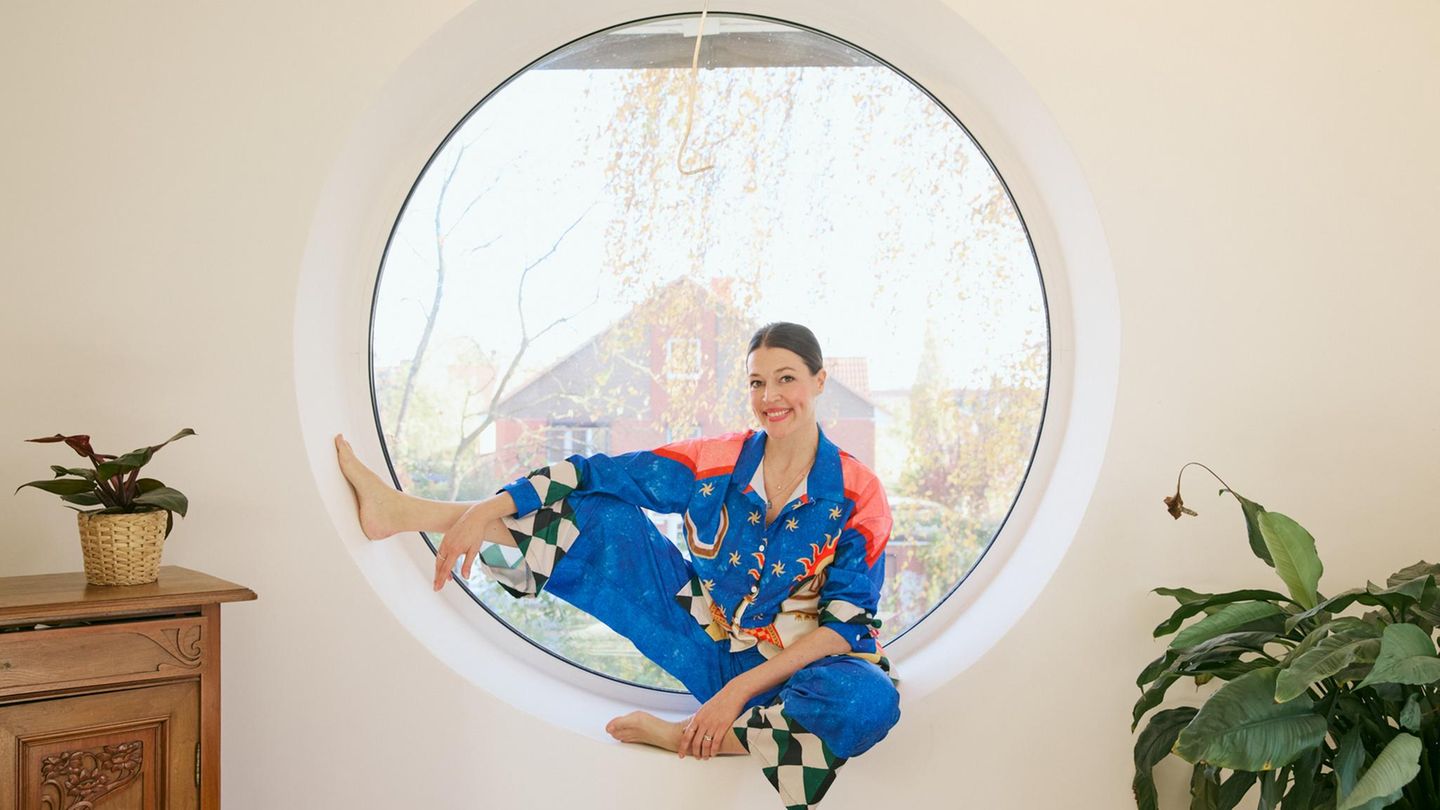 Sex-Expertin Lisa Opel sitzt in einem runden Fenster und lächelt in die Kamera.