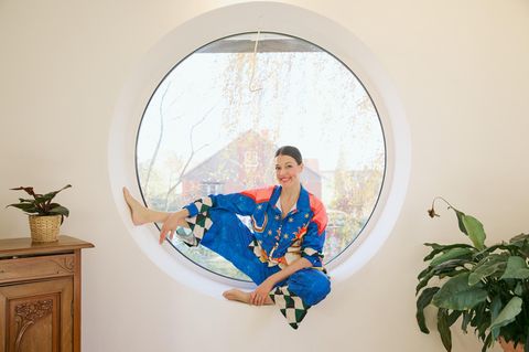 Sex-Expertin Lisa Opel sitzt in einem runden Fenster und lächelt in die Kamera.