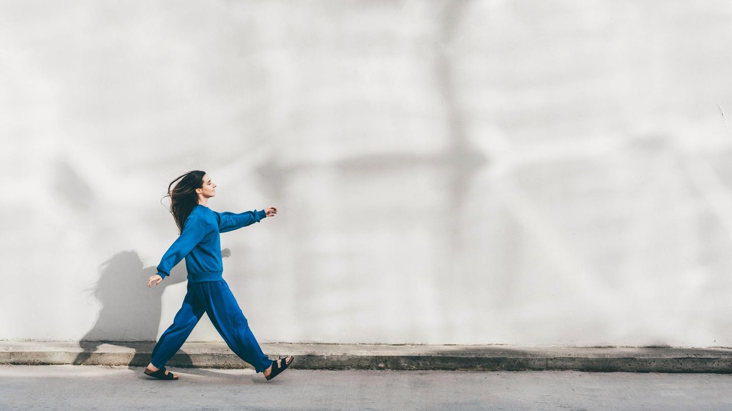 Intervalltraining: Eine junge Frau geht beschwingt die Straße entlang