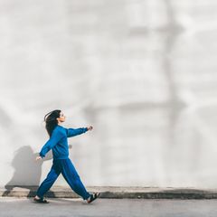 Intervalltraining: Eine junge Frau geht beschwingt die Straße entlang