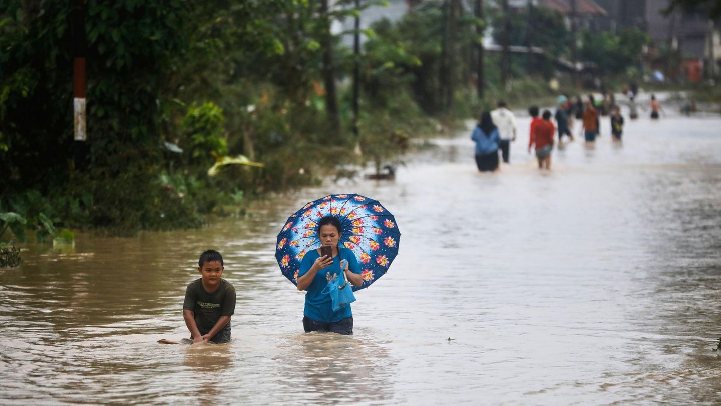 Menschen waten durch das Wasser einer überfluteten Straße
