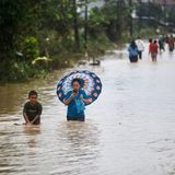 Menschen waten durch das Wasser einer überfluteten Straße