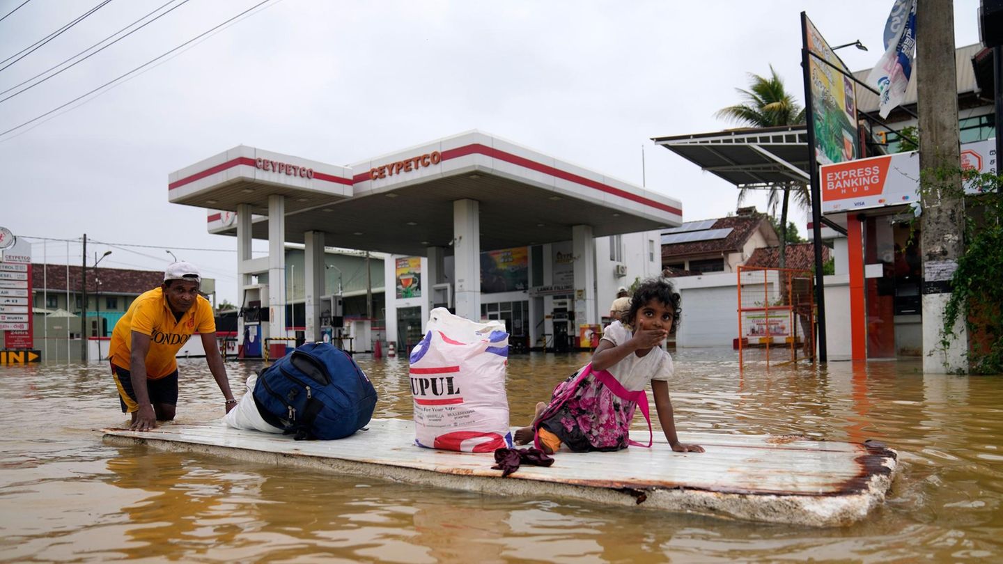 Mit einem behelfsmäßigen Floß bringt dieser Mann seine Habseligkeiten, ein Mädchen und sich selbst in Sicherheit