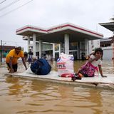 Mit einem behelfsmäßigen Floß bringt dieser Mann seine Habseligkeiten, ein Mädchen und sich selbst in Sicherheit