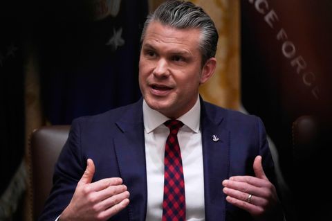 US-Verteidigungsminister Pete Hegseth sitzt an einem Tisch und weist mit beiden Händen auf sich