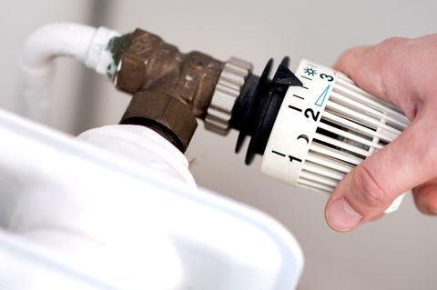 Eine rechte Hand dreht am Ventil eines Heikkörpers – Symbolbild Heizkosten