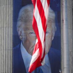 Foto von einem Bild von Donald Trump, eine US-amerikanische Fahne verdeckt das Gesicht halb