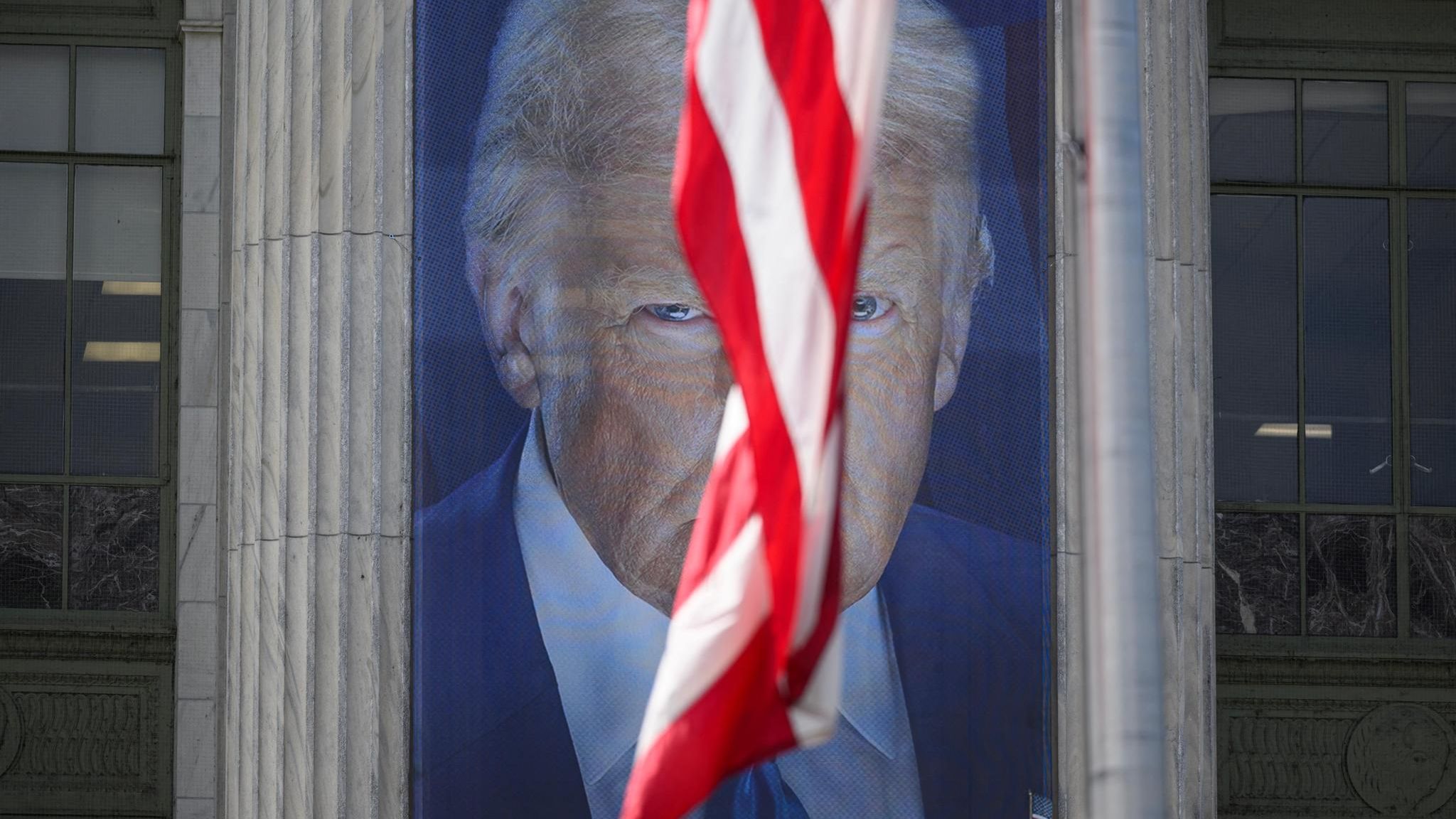 Foto von einem Bild von Donald Trump, eine US-amerikanische Fahne verdeckt das Gesicht halb