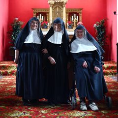 Drei Nonnen vor einem Altar