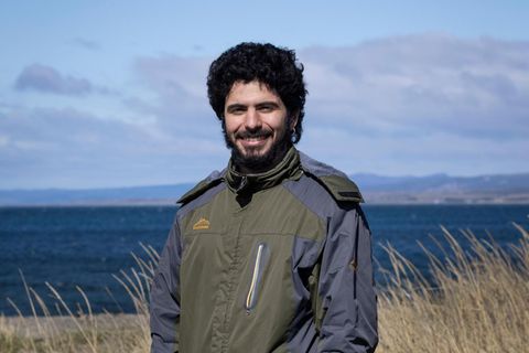 Adrián Simancas, 24, in Punta Arenas in Chile. Er steht in olivgrüner Jacke am Meer