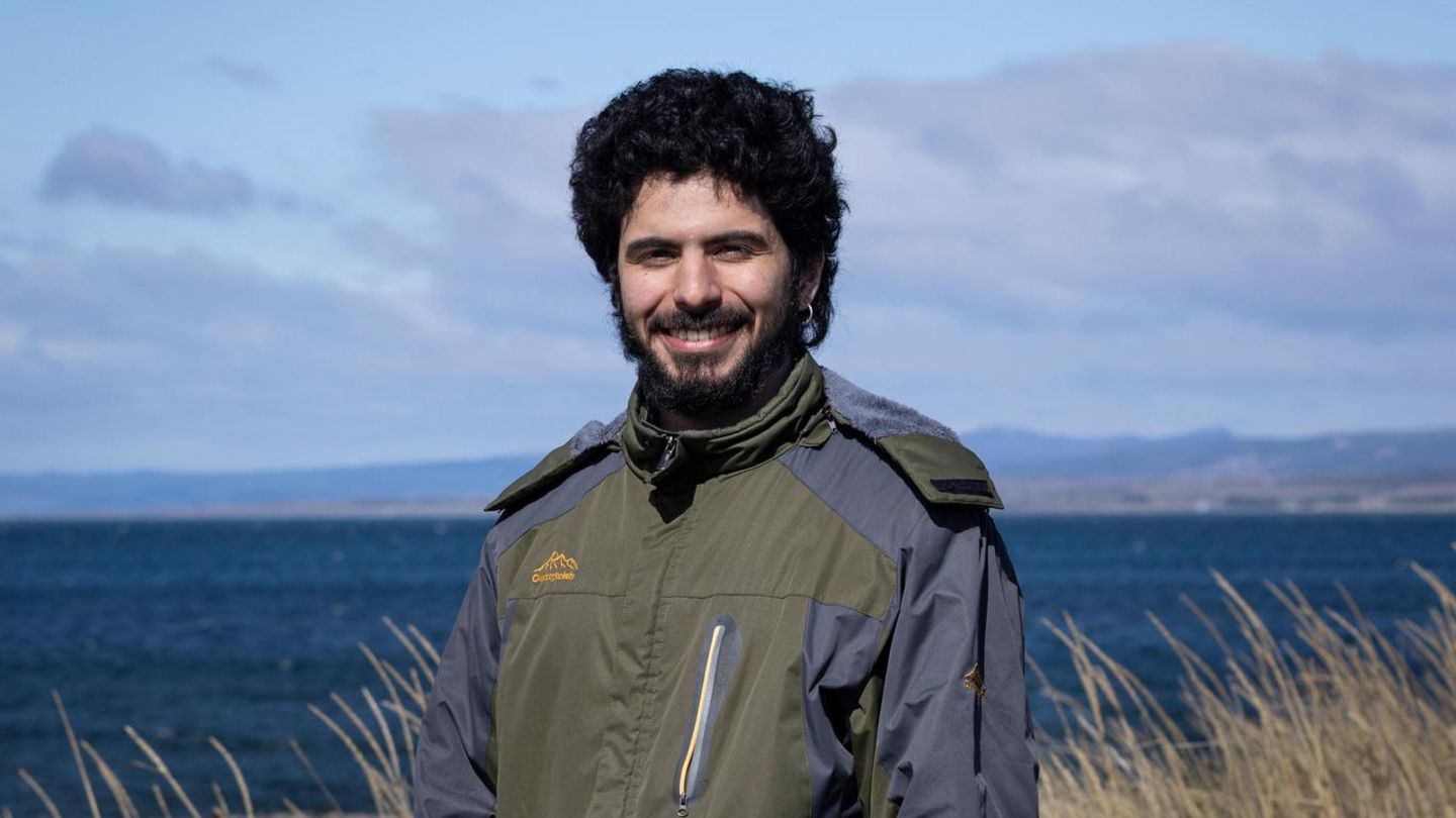Adrián Simancas, 24, in Punta Arenas in Chile. Er steht in olivgrüner Jacke am Meer