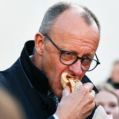 Friedrich Merz beißt in eine Bratwurst