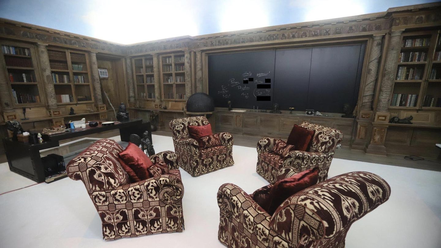 Ein opulentes Büro mit Bibliothek. Auf einer großen Tafel sind Worte gekritzelt
